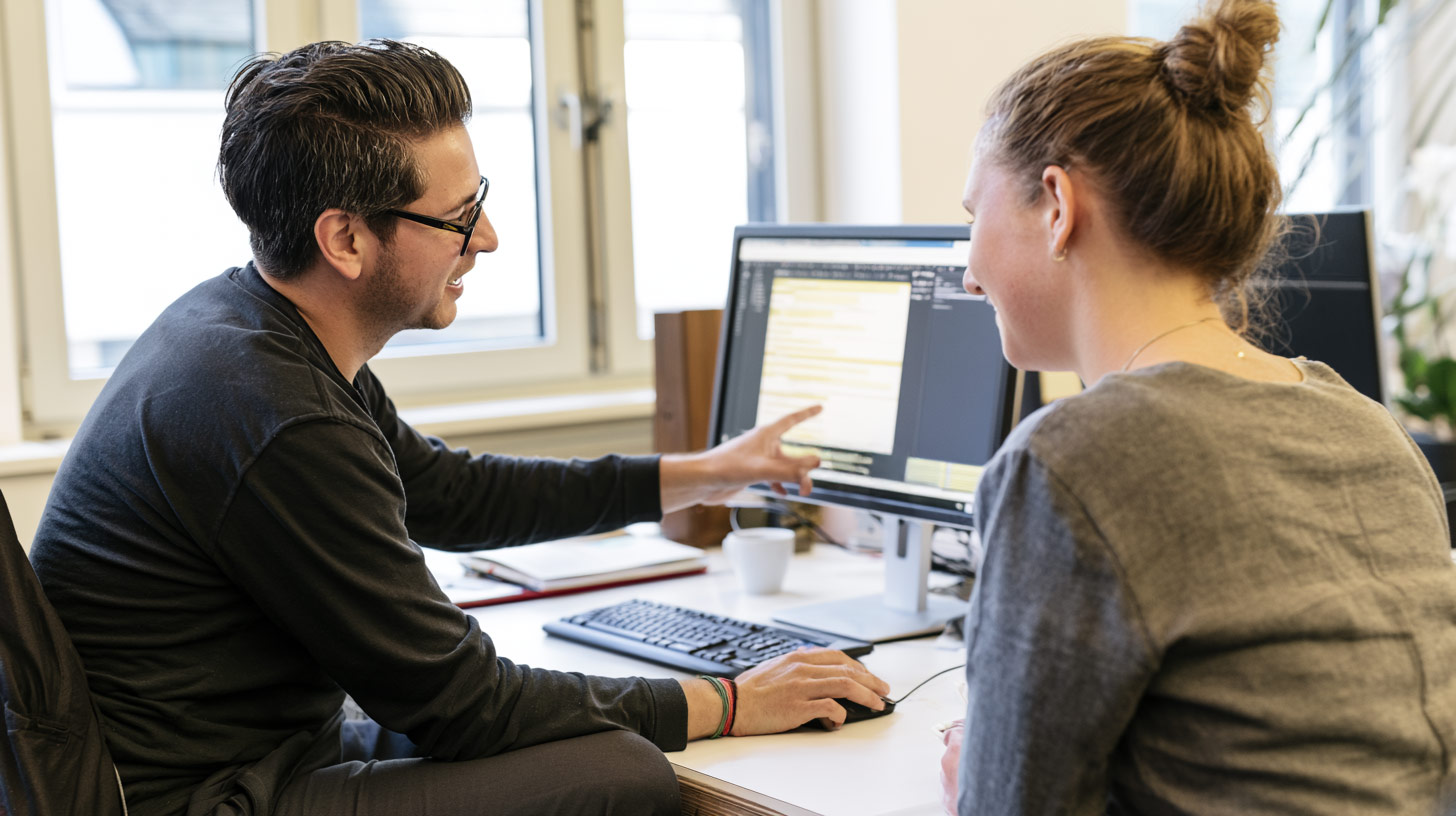 Zwei IT-Mitarbeitende besprechen gemeinsam eine Softwareanwendung am Bildschirm